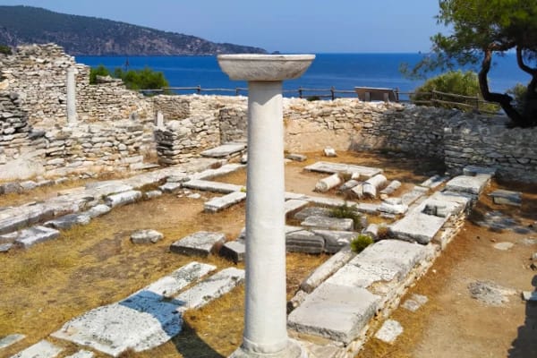 Ancient greek temple ruins and an erect marble pillar in the foreground at Aliki, Thassos